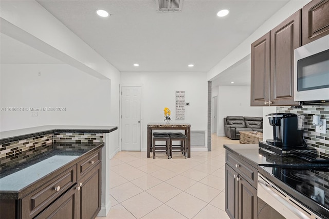 kitchen featuring backsplash, dark brown cabinets, and light tile patterned floors