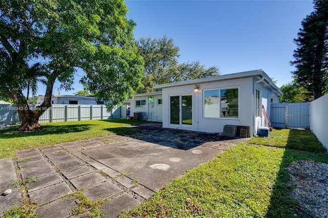 rear view of property with a lawn, central AC, and a patio