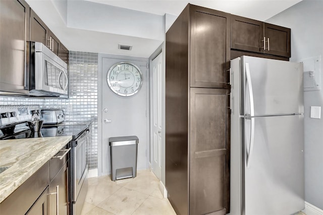 kitchen featuring light stone counters, light tile patterned floors, stainless steel appliances, and dark brown cabinetry