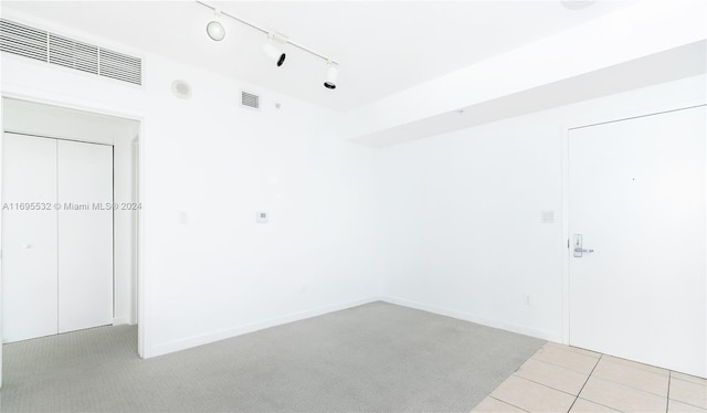 unfurnished room with rail lighting and light carpet