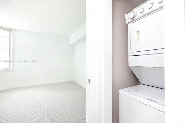 laundry room with carpet flooring and stacked washer / dryer