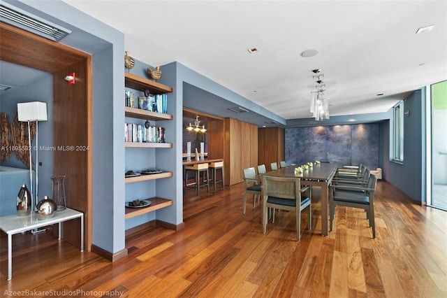 dining space featuring hardwood / wood-style floors, built in features, and a notable chandelier