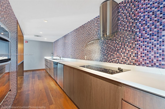 kitchen featuring black electric stovetop, tasteful backsplash, light hardwood / wood-style flooring, and sink