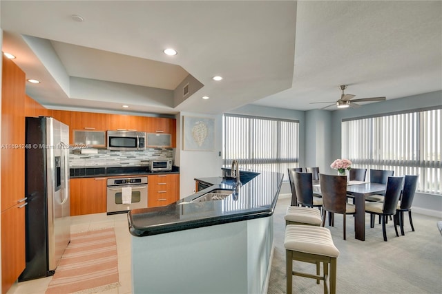 kitchen featuring ceiling fan, sink, tasteful backsplash, light carpet, and appliances with stainless steel finishes