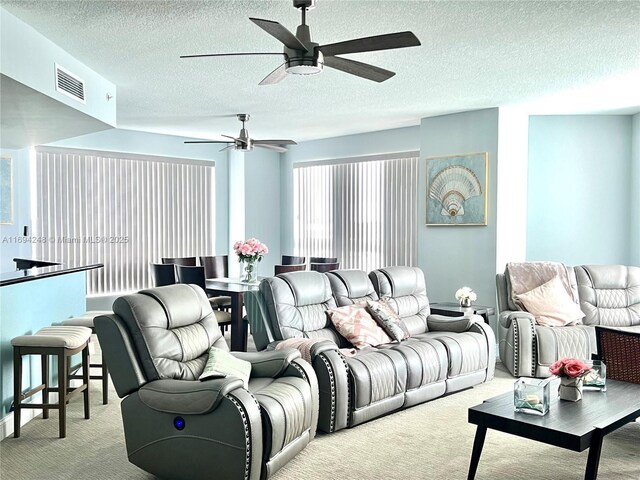 living room with ceiling fan, a textured ceiling, a wealth of natural light, and light carpet