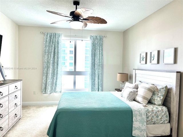 bedroom featuring a textured ceiling, ceiling fan, and light carpet