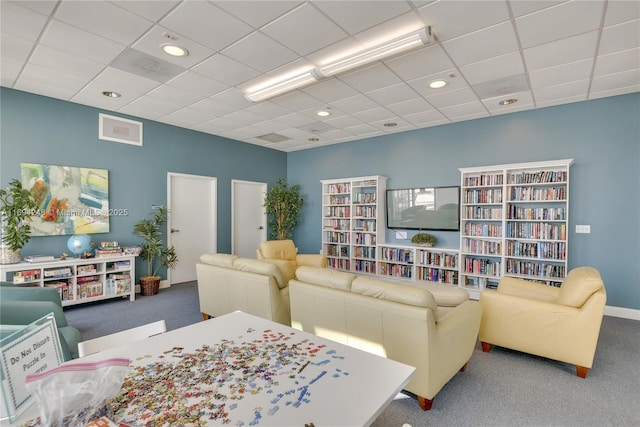 carpeted living room featuring a drop ceiling