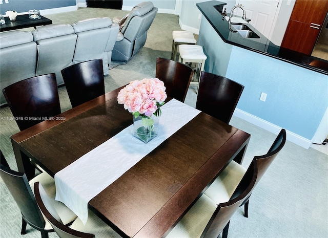 dining room featuring sink and light colored carpet