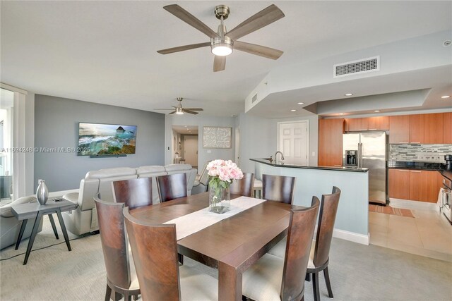 tiled dining room with ceiling fan and sink