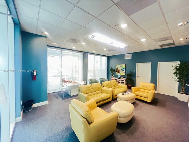 living room with a paneled ceiling and carpet floors