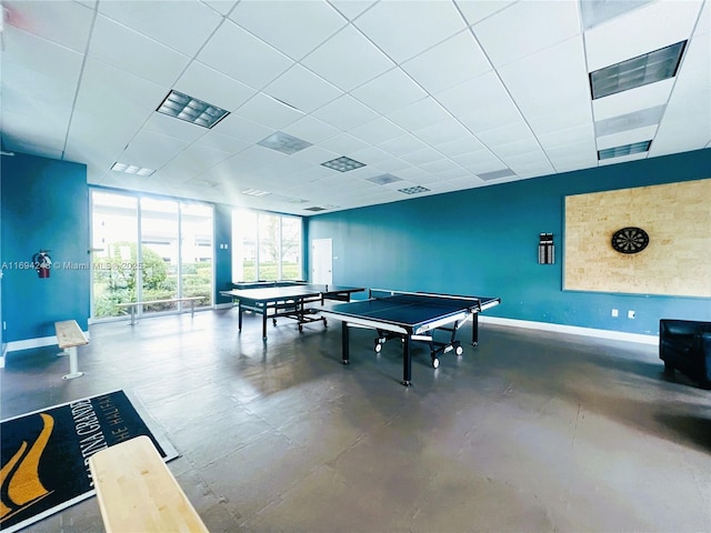 recreation room featuring a paneled ceiling and concrete floors