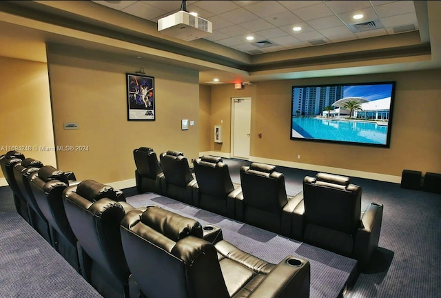 carpeted cinema featuring a paneled ceiling and a raised ceiling