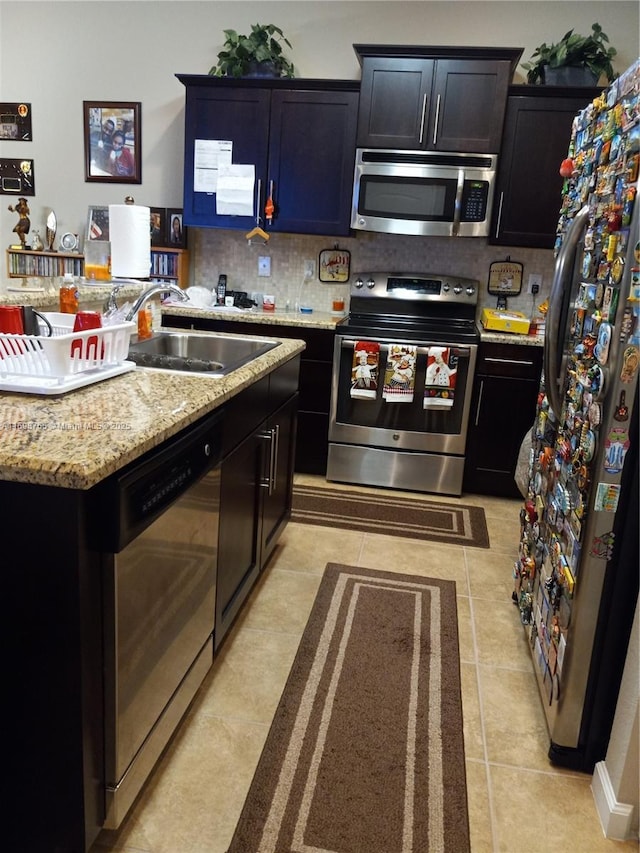 kitchen with sink, backsplash, light stone countertops, light tile patterned flooring, and stainless steel appliances