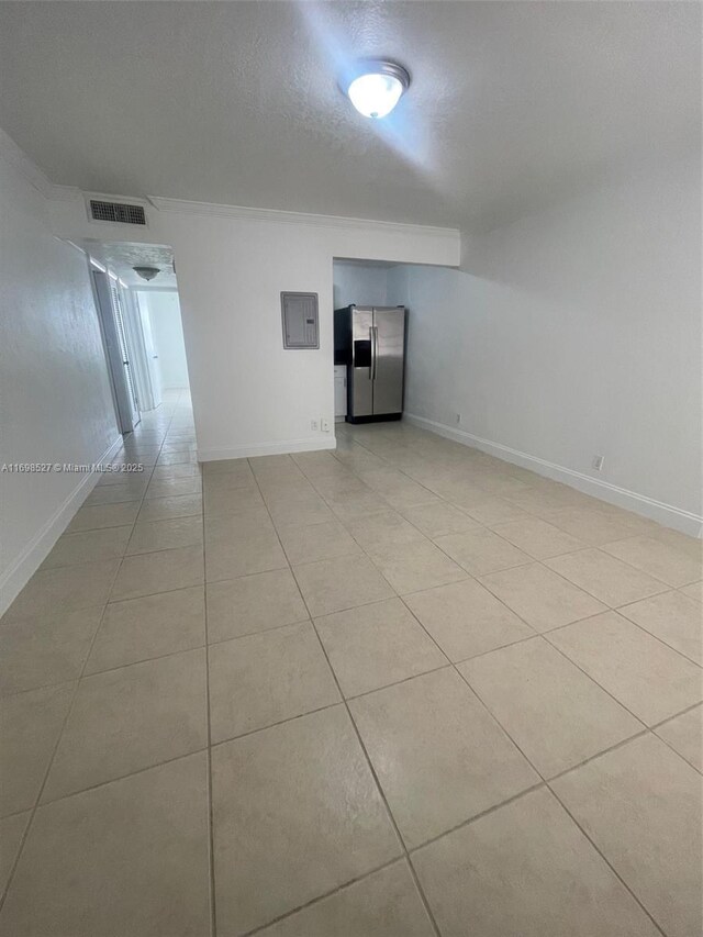 tiled empty room featuring ornamental molding, a textured ceiling, and electric panel