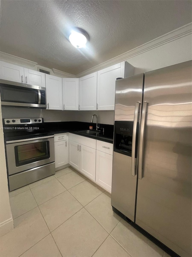 kitchen with white cabinets, a textured ceiling, stainless steel appliances, and sink