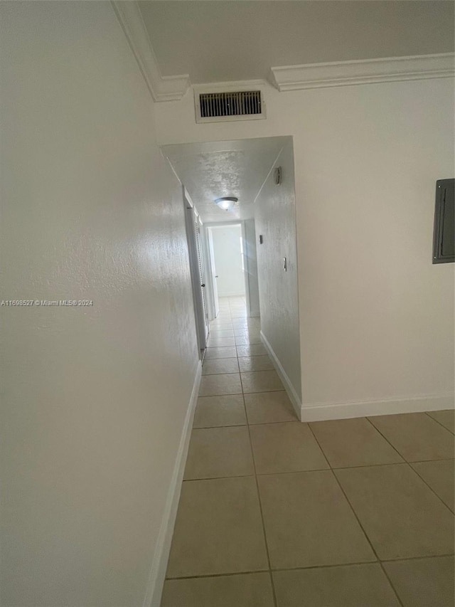 hallway featuring light tile patterned floors and ornamental molding