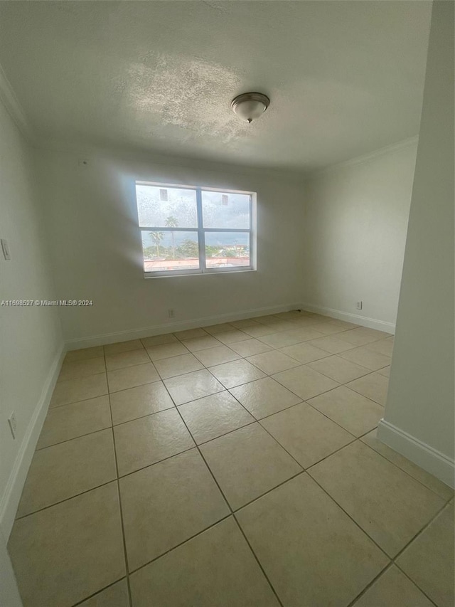 spare room with ornamental molding and light tile patterned flooring