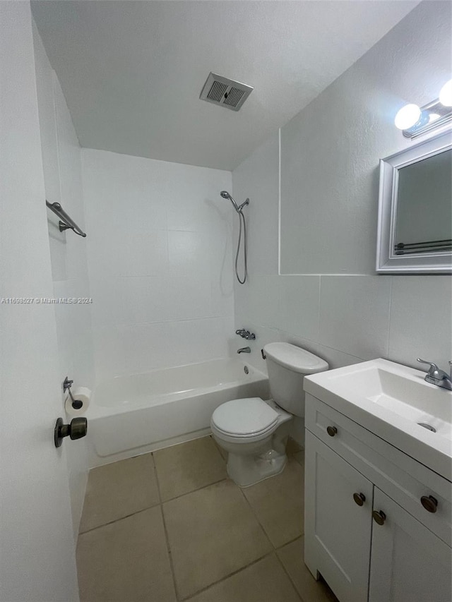 full bathroom with vanity, bathtub / shower combination, tile patterned flooring, toilet, and tile walls