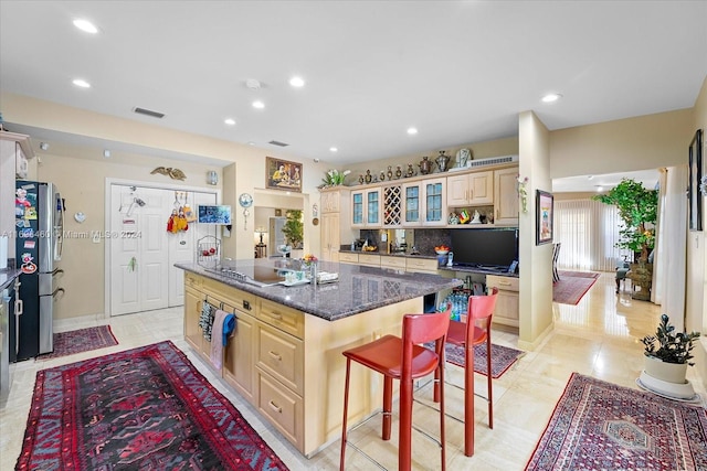 kitchen featuring dark stone countertops, a center island, stainless steel refrigerator, a breakfast bar area, and light tile patterned flooring