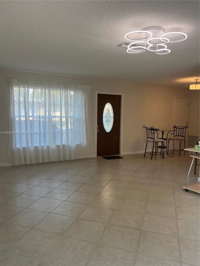 tiled foyer with an inviting chandelier, plenty of natural light, and a textured ceiling