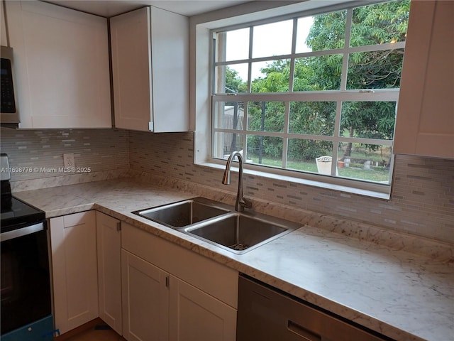 kitchen with range with electric stovetop, sink, white cabinets, and backsplash