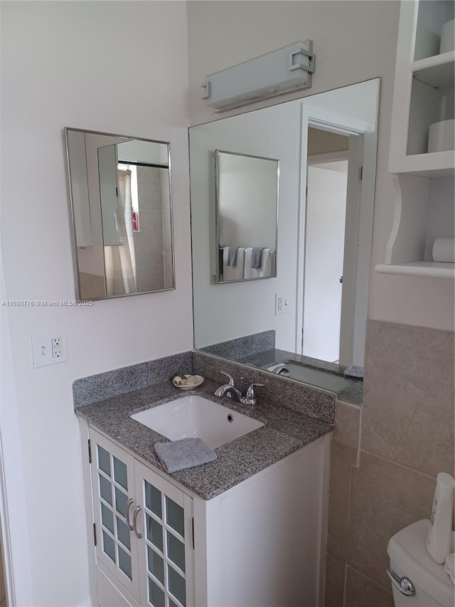 bathroom featuring vanity, toilet, and tile walls