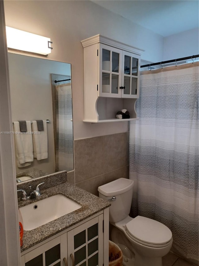 bathroom featuring vanity, tile walls, walk in shower, and toilet