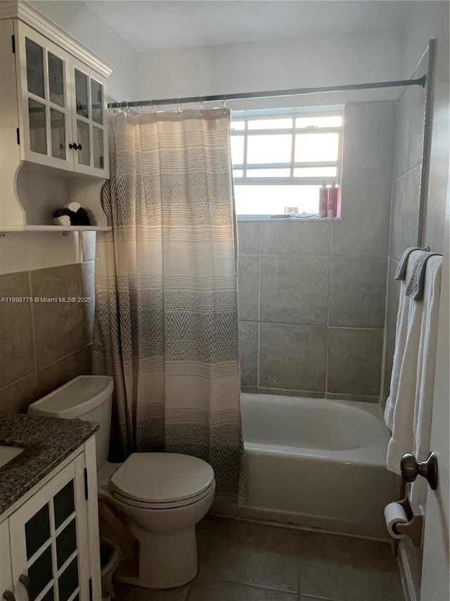 full bathroom with shower / bathtub combination with curtain, tile walls, vanity, tile patterned floors, and toilet