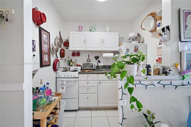 kitchen featuring white cabinetry, light tile patterned flooring, and white range