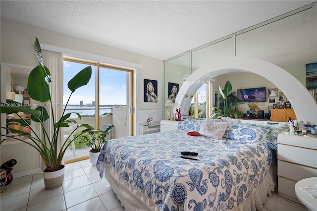 bedroom featuring access to exterior, light tile patterned floors, and a textured ceiling