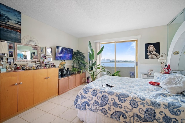 bedroom featuring light tile patterned floors, a textured ceiling, and access to outside