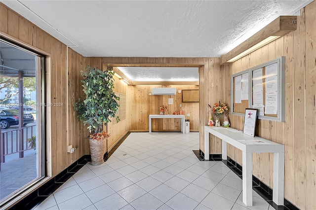 hallway featuring light tile patterned floors, a textured ceiling, and wooden walls