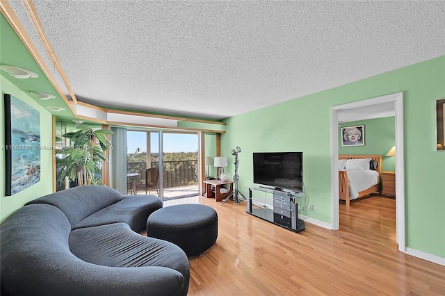 living area with a textured ceiling, baseboards, and wood finished floors