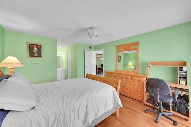 bedroom featuring visible vents, a textured ceiling, a ceiling fan, and wood finished floors