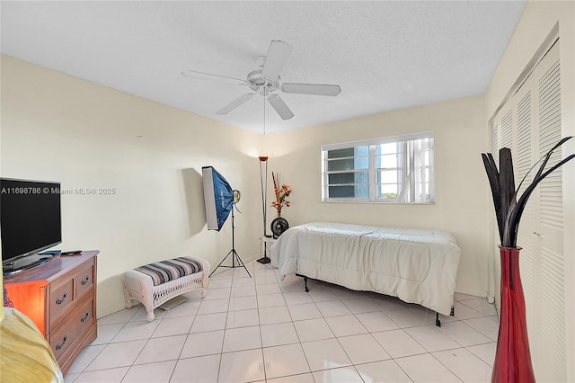 bedroom featuring light tile patterned flooring, ceiling fan, and a textured ceiling