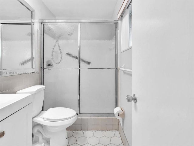 bathroom featuring tile patterned flooring, vanity, toilet, and an enclosed shower