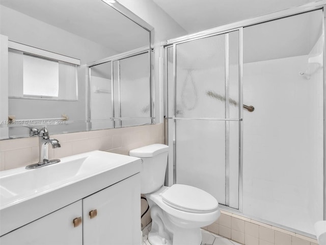 bathroom featuring tile patterned floors, an enclosed shower, vanity, tile walls, and toilet