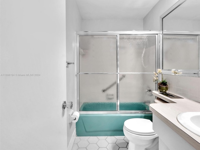 full bathroom featuring vanity, shower / bath combination with glass door, tile patterned flooring, toilet, and tasteful backsplash