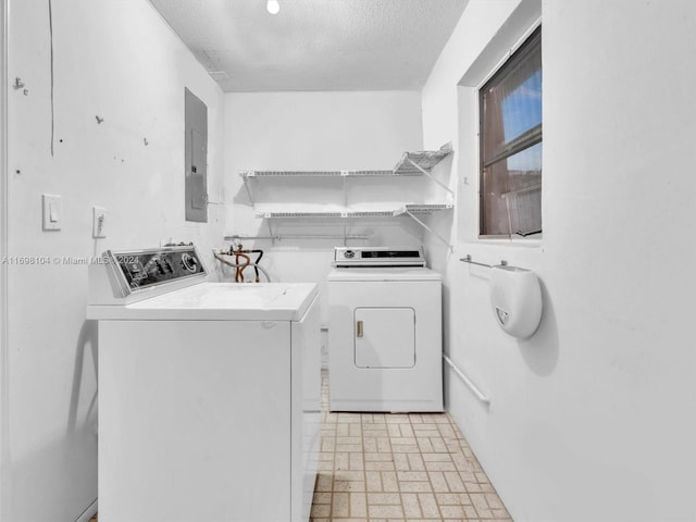 laundry area featuring washing machine and clothes dryer, electric panel, and a textured ceiling