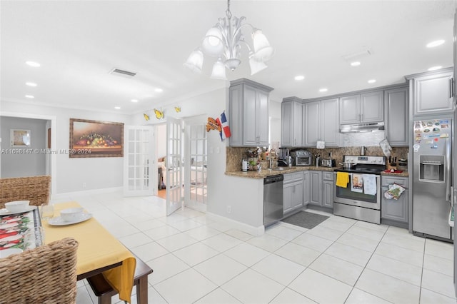 kitchen featuring appliances with stainless steel finishes, backsplash, an inviting chandelier, gray cabinets, and hanging light fixtures