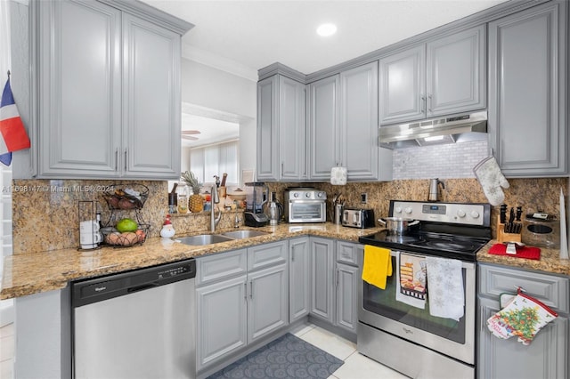 kitchen featuring sink, light tile patterned floors, light stone countertops, ornamental molding, and appliances with stainless steel finishes