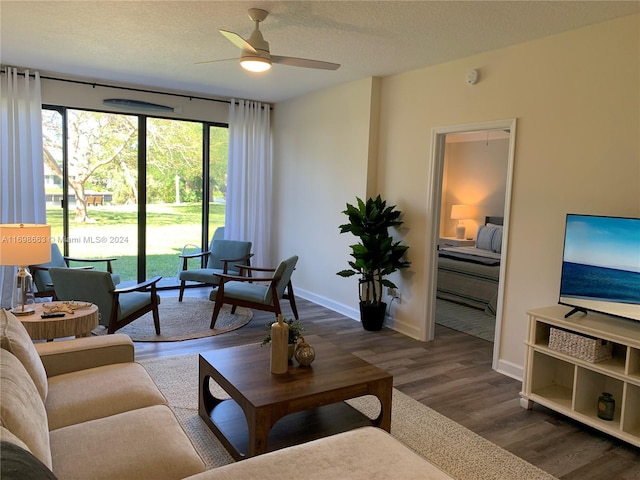 living room featuring a textured ceiling, ceiling fan, and dark wood-type flooring