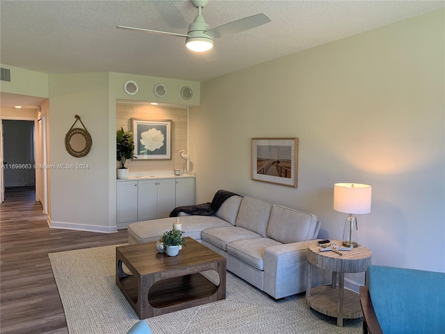 living room with ceiling fan, hardwood / wood-style floors, and a textured ceiling