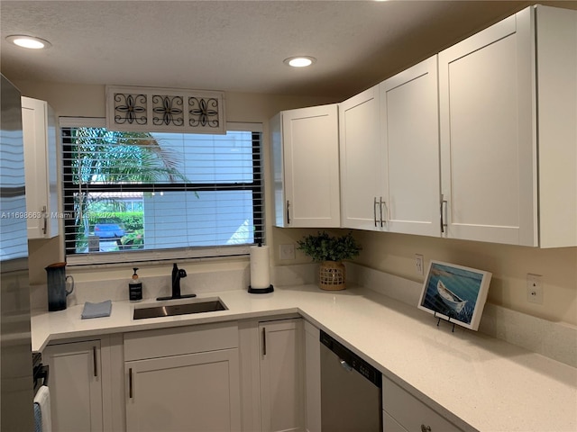 kitchen featuring stainless steel dishwasher, white cabinetry, sink, and a textured ceiling