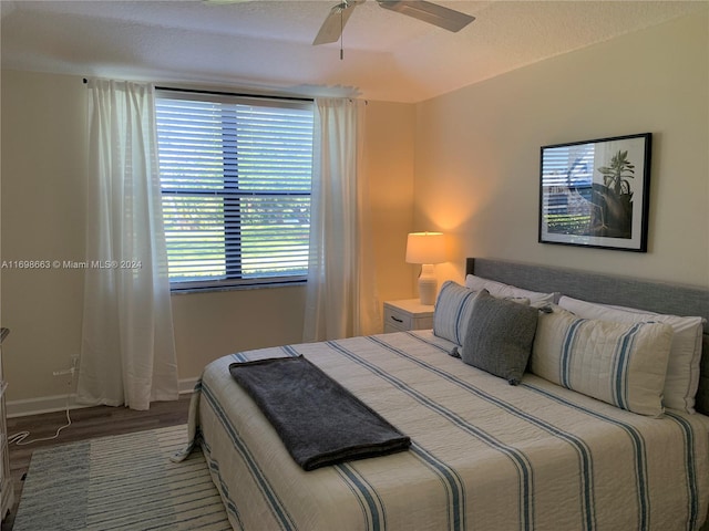 bedroom with hardwood / wood-style floors, ceiling fan, and a textured ceiling