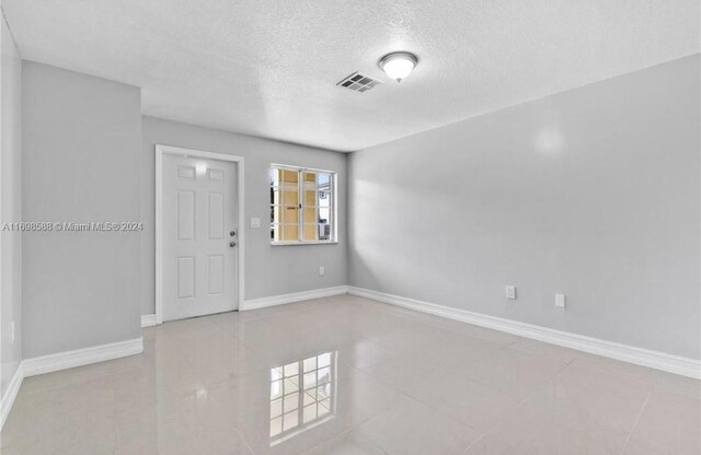 tiled empty room with a textured ceiling