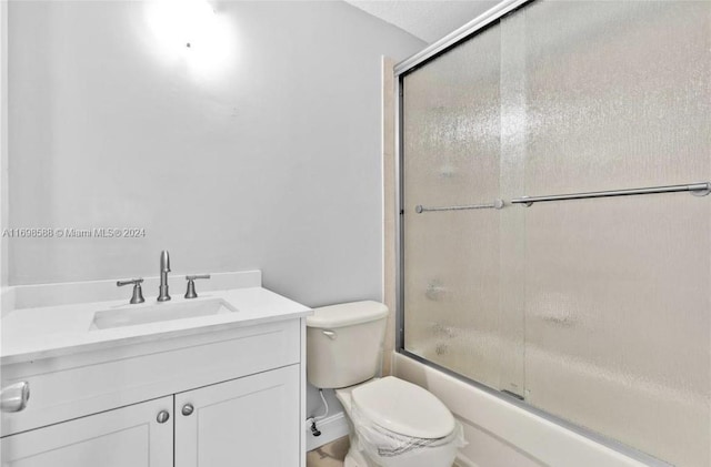 full bathroom with combined bath / shower with glass door, toilet, and vanity