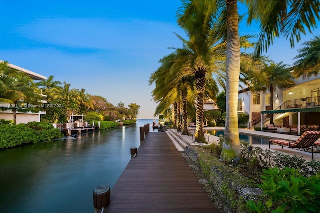 view of dock featuring a patio area, a balcony, and a water view