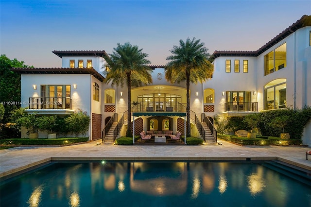 back house at dusk with an outdoor living space and a patio area