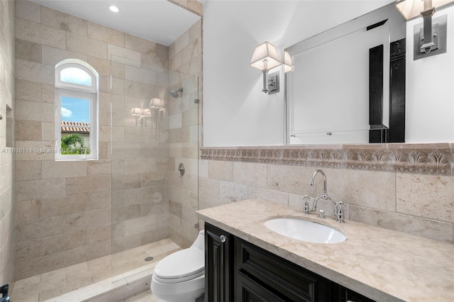 bathroom featuring vanity, toilet, tiled shower, and tile walls